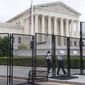 Security walks behind anti-scaling fencing, May 13, 2022, outside the Supreme Court in Washington. (AP Photo/Jacquelyn Martin, File)
