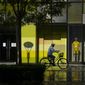 A woman wearing a face mask rides a bicycle past stores closed for COVID-19 control at a shopping mall in Beijing, Tuesday, May 17, 2022. (AP Photo/Mark Schiefelbein)