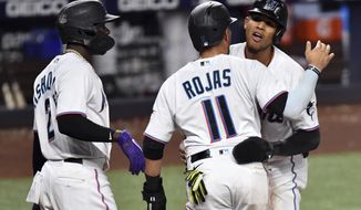 Miami Marlins&#39; Erik Gonzalez, right, and Miguel Rojas (11) celebrate scoring runs during the seventh inning of a baseball game against the Washington Nationals as teammate Jazz Chisholm Jr. (2) looks on, Tuesday, May 17, 2022, in Miami. (AP Photo/Jim Rassol)