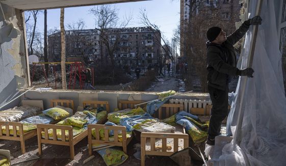 FILE - A man removes a destroyed curtain inside a school damaged among other residential buildings in Kyiv, Ukraine, Friday, March 18, 2022. As of early May, the Ukrainian government says Russia has shelled more than 1,000 schools, completely destroying 95. (AP Photo/Rodrigo Abd, File)