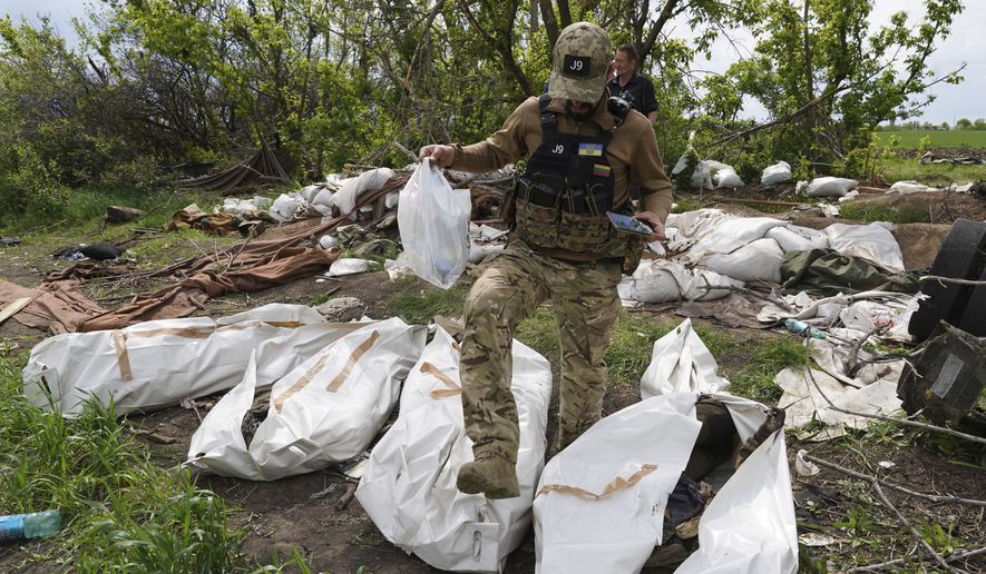 A Ukrainian serviceman works during the exhumation of killed Russian soldiers at their former positions near the village of Malaya Rohan, on the outskirts of Kharkiv, Wednesday May 18, 2022. (AP Photo/Andrii Marienko)