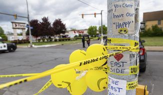 Signs, balloons and police tape are wrapped around a pole across from Tops Friendly Market on Tuesday, May 17, 2022, in Buffalo, N.Y. Tops, the Buffalo grocery store where 10 Black people were killed in a racist shooting rampage, was more than a place to buy groceries. As the only supermarket for miles, residents say the store was a sort of community hub where they chatted with neighbors and caught up on each other’s lives. (AP Photo/Joshua Bessex)
