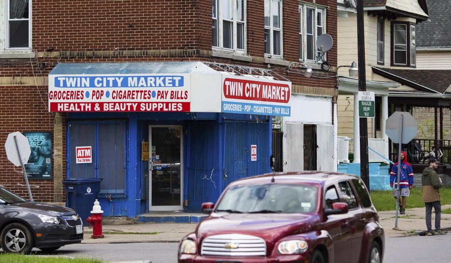 People walk and drive by Twin City Market, four blocks east of Tops Friendly Market, on Tuesday, May 17, 2022, in Buffalo, N.Y. (AP Photo/Joshua Bessex)