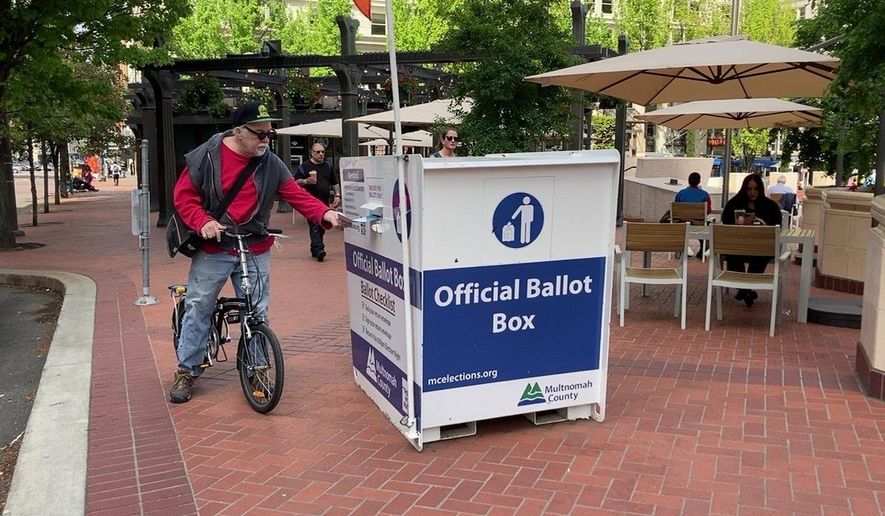 A voter drops off a ballot at a box in Pioneer Courthouse Square in Portland, Ore., Tuesday, May, 17, 2022. The state is holding its primary elections. (AP Photo/Gillian Flaccus)