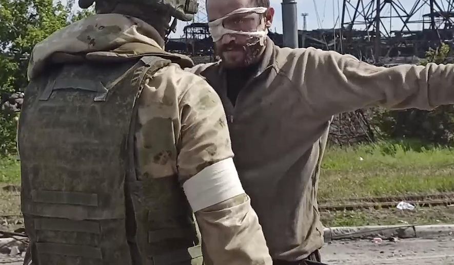 In this photo taken from a video released by the Russian Defense Ministry Press Service on Wednesday, May 18, 2022, a Russian serviceman frisks a Ukrainian soldier after he left the besieged Azovstal steel plant in Mariupol, Ukraine. (Russian Defense Ministry Press Service via AP)
