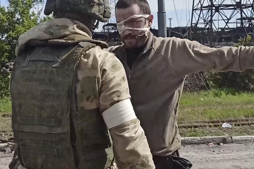 In this photo taken from a video released by the Russian Defense Ministry Press Service on Wednesday, May 18, 2022, a Russian serviceman frisks a Ukrainian soldier after he left the besieged Azovstal steel plant in Mariupol, Ukraine. (Russian Defense Ministry Press Service via AP)