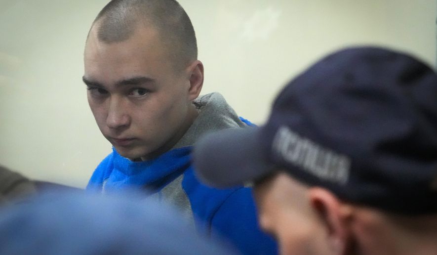 Russian army Sgt. Vadim Shishimarin, 21, is seen behind glass during a court hearing in Kyiv, Ukraine, Wednesday, May 18, 2022. The Russian soldier has gone on trial in Ukraine for the killing of an unarmed civilian. The case that opened in Kyiv marked the first time a member of the Russian military has been prosecuted for a war crime since Russia invaded Ukraine 11 weeks ago. (AP Photo/Efrem Lukatsky)