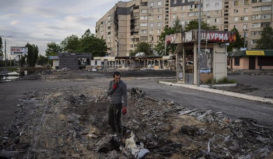 A man searches for metal scraps in a shelled neighbourhood in Kharkiv, eastern Ukraine, Thursday, May 19, 2022. (AP Photo/Bernat Armangue)