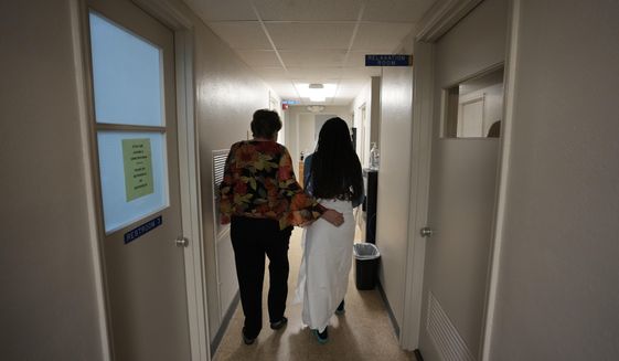 FILE - A 33-year-old mother of three from central Texas is escorted down the hall by clinic administrator Kathaleen Pittman prior to getting an abortion, Oct. 9, 2021, at Hope Medical Group for Women in Shreveport, La. Reproductive rights advocates are planning to open new abortion clinics or expand the capacity of existing ones in states without restrictive abortion laws. (AP Photo/Rebecca Blackwell, File)