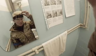 Yuliia Paievska, known as Taira, looks in the mirror and turns off her camera in Mariupol, Ukraine on Feb. 27, 2022. Using a body camera, she recorded her team&#39;s frantic efforts to bring people back from the brink of death. (Yuliia Paievska via AP)