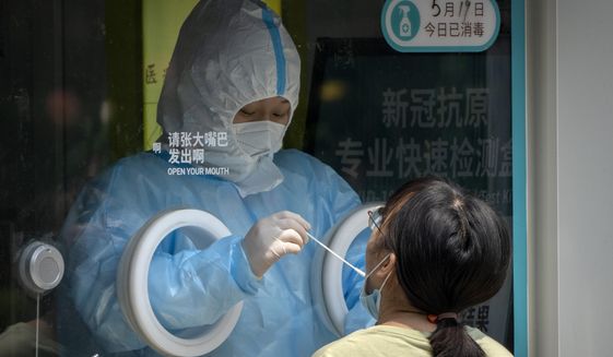 A worker wearing a protective suit administers a COVID-19 test at a coronavirus testing site in Beijing, Thursday, May 19, 2022. Parts of Beijing on Thursday halted daily mass testing that had been conducted over the past several weeks, but many testing sites remained busy due to requirements for a negative COVID test in the last 48 hours to enter some buildings in China&#39;s capital. (AP Photo/Mark Schiefelbein)