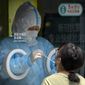 A worker wearing a protective suit administers a COVID-19 test at a coronavirus testing site in Beijing, Thursday, May 19, 2022. Parts of Beijing on Thursday halted daily mass testing that had been conducted over the past several weeks, but many testing sites remained busy due to requirements for a negative COVID test in the last 48 hours to enter some buildings in China&#39;s capital. (AP Photo/Mark Schiefelbein)