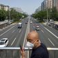 A man wearing a face mask stands on a bridge over an expressway in Beijing, Thursday, May 19, 2022. Parts of Beijing on Thursday halted daily mass testing that had been conducted over the past several weeks, but many testing sites remained busy due to requirements for a negative COVID test in the last 48 hours to enter some buildings in China&#39;s capital. (AP Photo/Mark Schiefelbein)