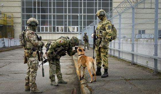 Russian troops pet their military dog as they guard an entrance of the Kakhovka Hydroelectric Station, a run-of-river power plant on the Dnieper River in Kherson region, south Ukraine, Friday, May 20, 2022. The Kherson region has been under control of the Russian forces since the early days of the Russian military action in Ukraine. This photo was taken during a trip organized by the Russian Ministry of Defense. (AP Photo) **FILE**