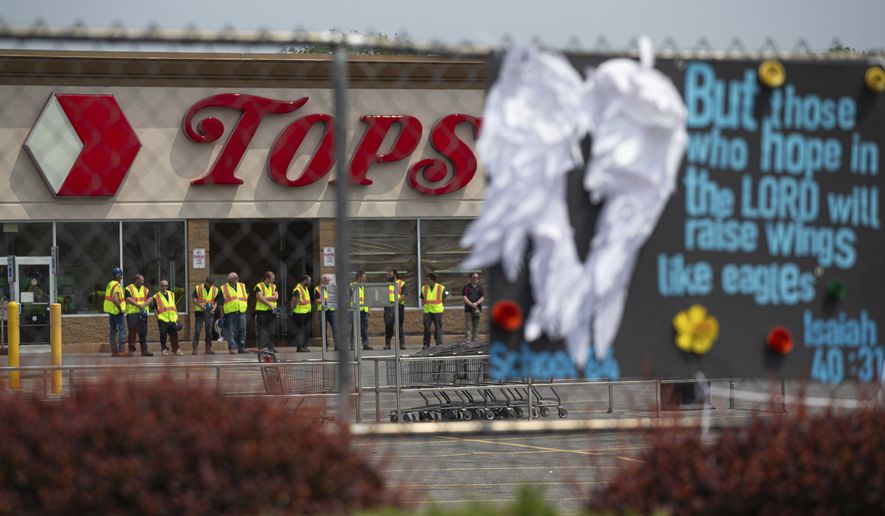 Investigators stand outside during a moment of silence for the victims of the Buffalo supermarket shooting outside the Tops Friendly Market on Saturday, May 21, 2022, in Buffalo, N.Y.  Tops was encouraging people to join its stores in a moment of silence to honor the shooting victims Saturday at 2:30 p.m., the approximate time of the attack a week earlier. Buffalo Mayor Byron Brown also called for 123 seconds of silence from 2:28 p.m. to 2:31 p.m., followed by the ringing of church bells 13 times throughout the city to honor the 10 people killed and three wounded. (AP Photo/Joshua Bessex)
