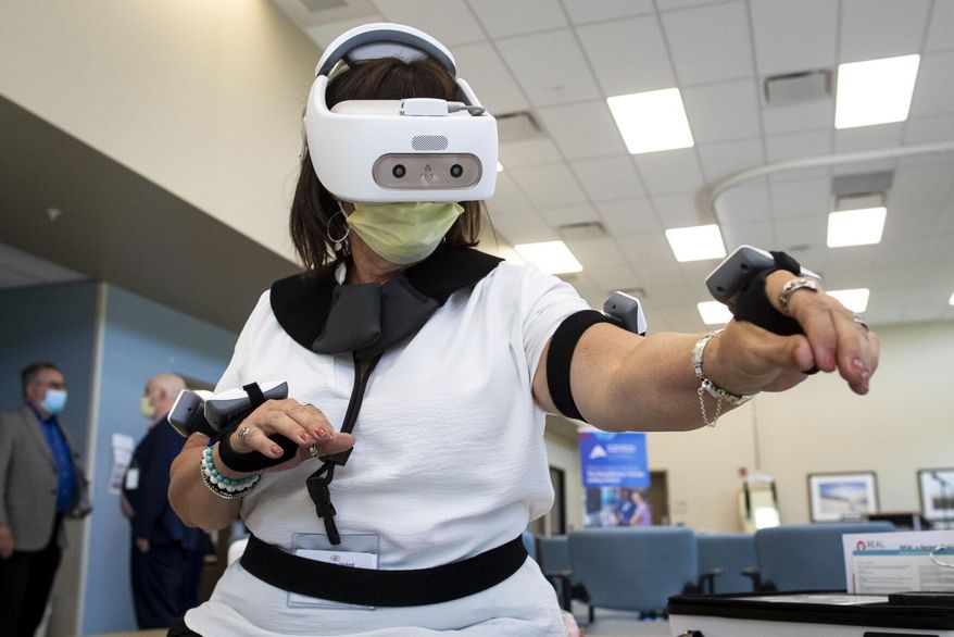 Laurie Brown tries out a virtual reality rehabilitation tool during an open house at the Rehabilitation Hospital of Montana in Billings on Wednesday, May 18,2022. The hospital uses the technology to help patents who have suffered from strokes and other medical problems. (Mike Clark/The Billings Gazette via AP)
