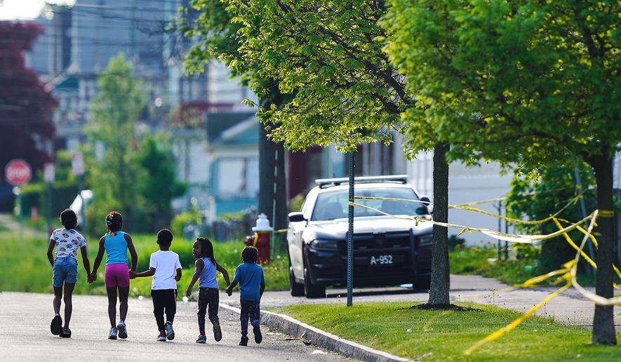 Children walk hand-in-hand near the scene of a shooting at a supermarket in Buffalo, N.Y., May 15, 2022. The shooting rampage at a Buffalo supermarket, carried out by an 18-year-old who was flagged for making a threatening comment at his high school the year before, highlights concerns over whether schools are adequately supporting and screening students. (AP Photo/Matt Rourke, File)