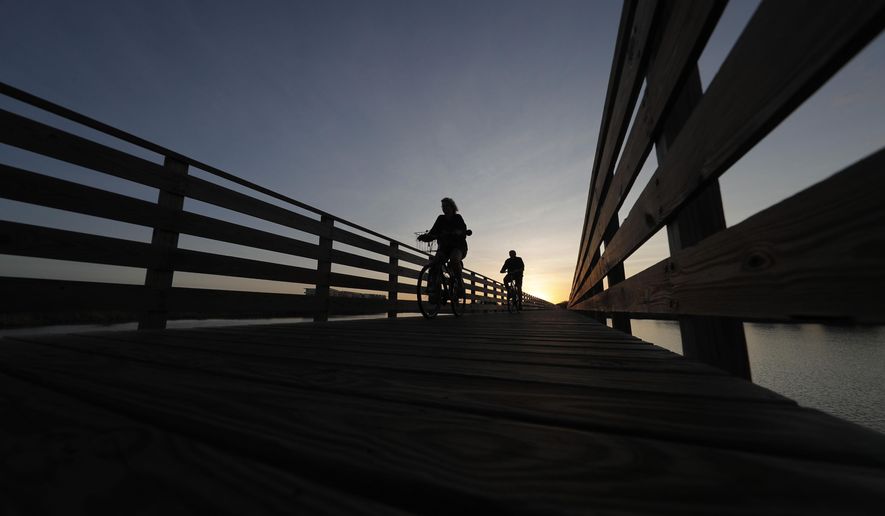 Bike riders cross over a boardwalk at Gulf State Park in Gulf Shores, Ala., in this file photo from March 12, 2020. Alabama voters on Tuesday, May 24, 2022, will consider a constitutional amendment that would provide $85 million for improvements to state parks and historical sites. (AP Photo/Gerald Herbert, File)
