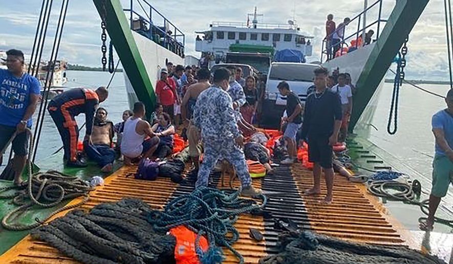 In this photo provided by the Philippine Coast Guard, passengers are checked after being rescued at the port of Real, Quezon province, Philippines Monday, May 23, 2022. A passenger ship caught fire as it nears their port of destination in Real town killing several people on board. (Philippine Coast Guard via AP Photo)