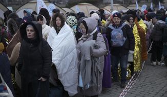 Refugees wait in a crowd for transportation after fleeing from the Ukraine and arriving at the border crossing in Medyka, Poland, Monday, March 7, 2022. Hundreds of thousands of Ukrainian civilians attempting to flee to safety Sunday were forced to shelter from Russian shelling that pummeled cities in Ukraine&#39;s center, north and south. (AP Photo/Markus Schreiber)