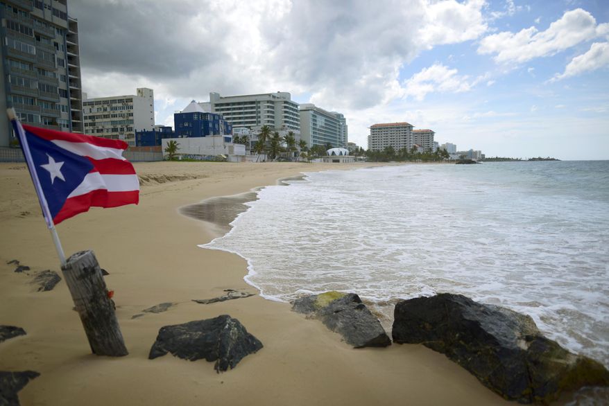 A Puerto Rican flag flies on an empty beach at Ocean Park, in San Juan, Puerto Rico, Thursday, May 21, 2020. More than 1,000 restaurants in the San Juan area were forced to shutter due to the pandemic, but many were able to survive by offering takeout and delivery options. Some created packages for holidays like Christmas, Thanksgiving and Mother's Day. (AP Photo/Carlos Giusti, File)