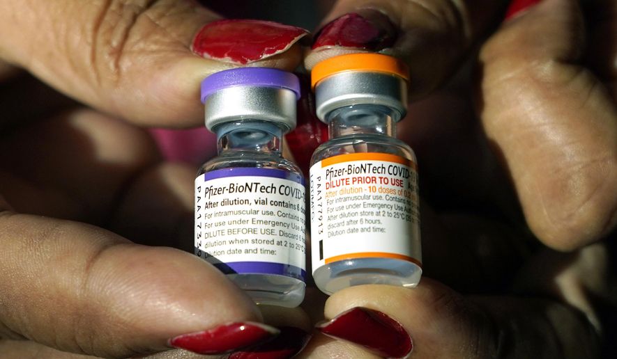 A nurse holds a vial of the Pfizer COVID-19 vaccine for children ages 5 to 11, right, and a vial of the vaccine for adults, which has a different colored label, at a vaccination station in Jackson, Miss., Tuesday, Feb. 8, 2022. (AP Photo/Rogelio V. Solis, File)
