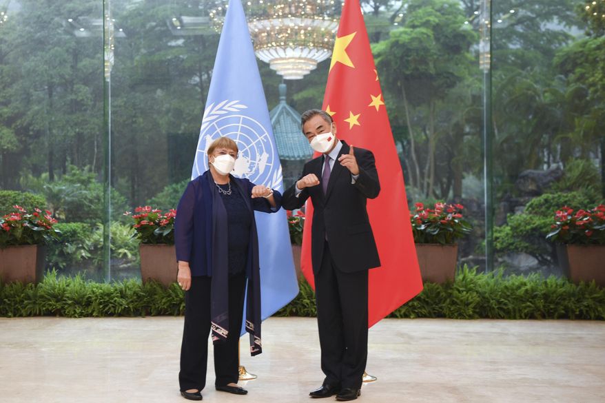 In this photo released by Xinhua News Agency, Chinese Foreign Minister Wang Yi, right, meets with the United Nations High Commissioner for Human Rights Michelle Bachelet in Guangzhou, southern China&#39;s Guangdong Province on Monday, May 23, 2022. (Deng Hua/Xinhua via AP)