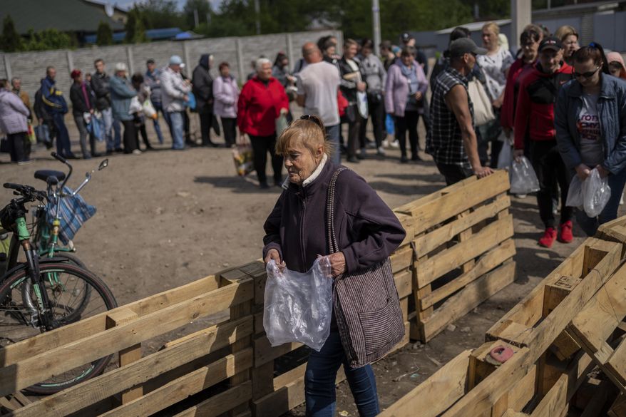 People queue to receive flour at a food donation spot in Kharkiv, eastern Ukraine, Monday, May 23, 2022. (AP Photo/Bernat Armangue)