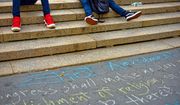 People sit on the steps of Union Square with the First Amendment written in chalk on the sidewalk. Photo credit: 26ShadesOfGreen via Shutterstock.