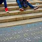 People sit on the steps of Union Square with the First Amendment written in chalk on the sidewalk. Photo credit: 26ShadesOfGreen via Shutterstock.