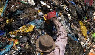 A waste picker rummages through garbage, at a dumping site in Johannesburg, South Africa, Friday, May 20, 2022. Environmental activists are gathering in South Africa this week to press governments and businesses to reduce the production of plastic because it is harming the continent&#39;s environment. (AP Photo/Themba Hadebe)