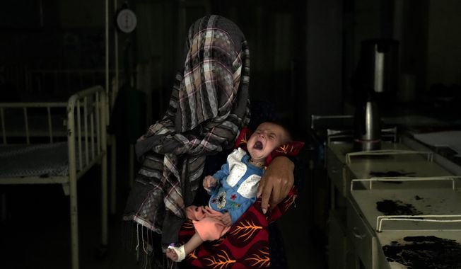 Nazia 30, who has lost four children due to severe malnutrition, holds her malnourished baby in a hospital in Parwan province north of Kabul, Afghanistan, Thursday, May 19, 2022. Some 1.1 million Afghan children under the age of five will face malnutrition by the end of the year. , as hospitals wards are already packed with sick children . (AP Photo/Ebrahim Noroozi)