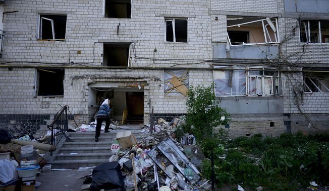 A residents enters her home building ruined by shelling in Borodyanka, Ukraine, Tuesday, May 24, 2022. No matter where Ukrainians live, the 3-month-old war never seems to be far away. Those in towns and villages near the front lines hide in basements from constant shelling, struggling to survive with no electricity or gas — and often no running water. (AP Photo/Natacha Pisarenko)