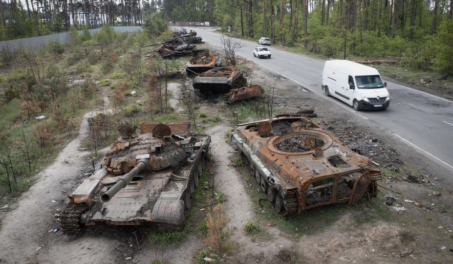 Cars pass by destroyed Russian tanks in a recent battle against Ukrainians in the village of Dmytrivka, close to Kyiv, Ukraine, Monday, May 23, 2022. No matter where Ukrainians live, the 3-month-old war never seems to be far away. Those in towns and villages near the front lines hide in basements from constant shelling, struggling to survive with no electricity or gas — and often no running water. (AP Photo/Efrem Lukatsky)