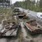 Cars pass by destroyed Russian tanks in a recent battle against Ukrainians in the village of Dmytrivka, close to Kyiv, Ukraine, Monday, May 23, 2022. No matter where Ukrainians live, the 3-month-old war never seems to be far away. Those in towns and villages near the front lines hide in basements from constant shelling, struggling to survive with no electricity or gas — and often no running water. (AP Photo/Efrem Lukatsky)
