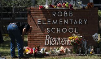 A law enforcement personnel lights a candle outside Robb Elementary School in Uvalde, Texas, Wednesday, May 25, 2022. Desperation turned to heart-wrenching sorrow for families of grade schoolers killed after an 18-year-old gunman barricaded himself in their Texas classroom and began shooting, killing several fourth-graders and their teachers. (AP Photo/Jae C. Hong)