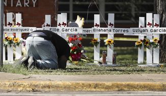 A mourner bows down in prayer at a memorial site for the victims of the Robb Elementary School shooting, Thursday, May 26, 2022, in Uvalde, Texas. (Kin Man Hui/The San Antonio Express-News via AP)