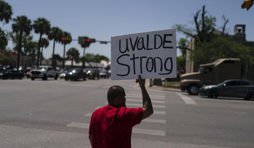 Alex Covarrubias, 32, holds up a sign at a street corner for the victims of Tuesday&#39;s shooting Robb Elementary School in Uvalde, Texas, Thursday, May 26, 2022. (AP Photo/Jae C. Hong)