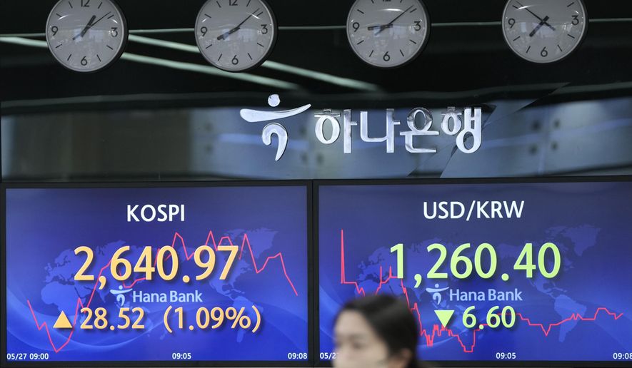 A currency trader walks by the screens showing the Korea Composite Stock Price Index (KOSPI), left, and the foreign exchange rate between U.S. dollar and South Korean won at a foreign exchange dealing room in Seoul, South Korea, Friday, May 27, 2022. Asian shares gained Friday as investors cheered a strong set of earnings from retailers that has sent U.S. shares higher. (AP Photo/Lee Jin-man)