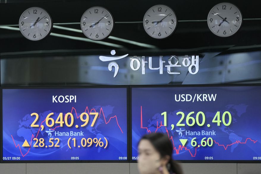 A currency trader walks by the screens showing the Korea Composite Stock Price Index (KOSPI), left, and the foreign exchange rate between U.S. dollar and South Korean won at a foreign exchange dealing room in Seoul, South Korea, Friday, May 27, 2022. Asian shares gained Friday as investors cheered a strong set of earnings from retailers that has sent U.S. shares higher. (AP Photo/Lee Jin-man)