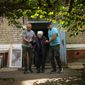 A woman is evacuated by volunteers of Vostok SOS charitable organisation in Kramatorsk, eastern Ukraine, Thursday, May 26, 2022. Residents in villages and towns near the front line continue to flee as fighting rages in eastern Ukraine. (AP Photo/Francisco Seco)