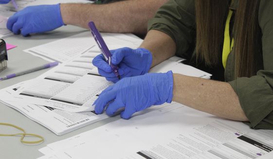 In this file photo, an election work in Clackamas County, Oregon, uses a purple maker to transfer votes from a spoiled ballot to a fresh one so the ball can be scanned in Oregon City, Oregon, on Wednesday, May 25, 2022. (AP Photo/Gillian Flaccus)  **FILE**