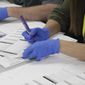 In this file photo, an election work in Clackamas County, Oregon, uses a purple maker to transfer votes from a spoiled ballot to a fresh one so the ball can be scanned in Oregon City, Oregon, on Wednesday, May 25, 2022. (AP Photo/Gillian Flaccus)  **FILE**