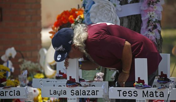 A man kisses the cross of Layla Salazar at a memorial outside Robb Elementary School to honor the victims killed in this week&#39;s school shooting in Uvalde, Texas, Saturday, May 28, 2022. (AP Photo/Dario Lopez-Mills)