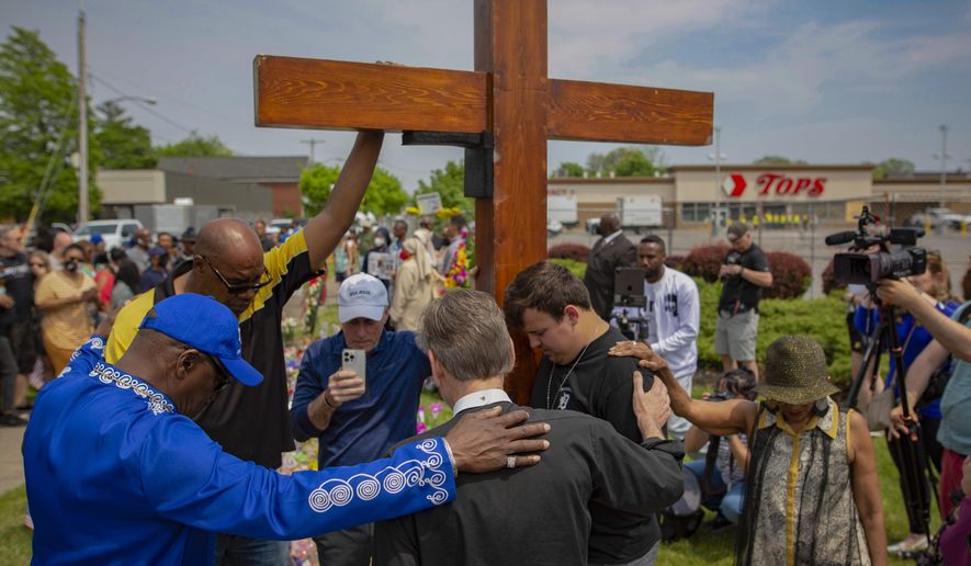 FILE - A group prays at the site of a memorial for the victims of the Buffalo supermarket shooting outside the Tops Friendly Market on Saturday, May 21, 2022, in Buffalo, N.Y. Funeral services are set for Friday for three of those killed: Geraldine Talley, Andre Mackniel and Margus Morrison. They are among the 10 people killed and three wounded May 14 when a white gunman opened fire on shoppers and employees at a Tops Friendly Market. (AP Photo/Joshua Bessex, File)