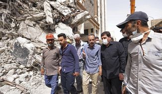 In this photo released by official website of the office of Iranian Senior Vice-President, on Friday, May 27, 2022, Vice-President Mohammad Mokhber, second right, visits the site of a tower at under construction 10-story Metropol Building which collapsed on Monday, in the southwestern city of Abadan, Iran. Rescue teams at the site of the tower pulled five more bodies from the rubble on Friday, bringing the death toll in the disaster to 24. (Iranian Senior Vice-President Office via AP)