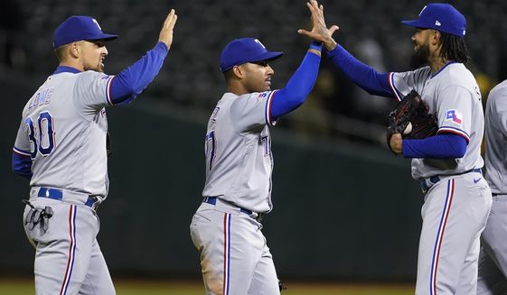 Texas Rangers&#39; Nathaniel Lowe, left, celebrates with Andy Ibanez and Dennis Santana, right, after the Rangers defeated the Oakland Athletics in a baseball game in Oakland, Calif., Friday, May 27, 2022. (AP Photo/Jeff Chiu)