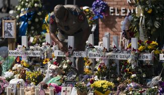 A state trooper places a tiara on a cross honoring Ellie Garcia, one of the victims killed in this week&#39;s elementary school shooting in Uvalde, Texas Saturday, May 28, 2022. (AP Photo/Jae C. Hong)