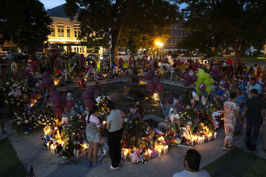 People visit a memorial set up in a town square to honor the victims killed in the elementary school shooting earlier in the week in Uvalde, Texas, late Saturday, May 28, 2022. (AP Photo/Jae C. Hong)