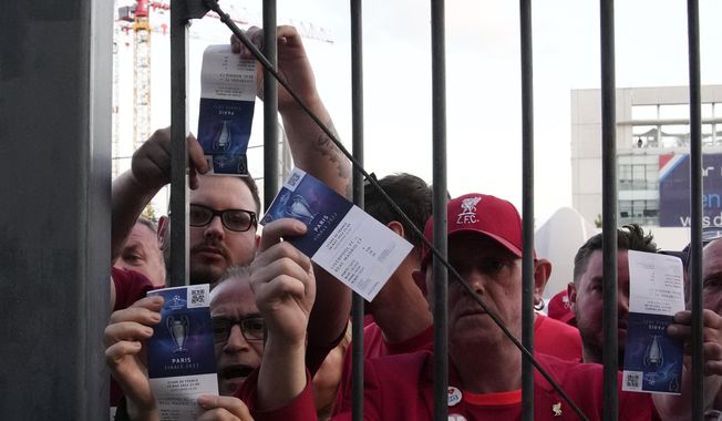 Fans shows tickets in front of the Stade de France prior the Champions League final soccer match between Liverpool and Real Madrid, in Saint Denis near Paris, Saturday, May 28, 2022. Police have deployed tear gas on supporters waiting in long lines to get into the Stade de France for the Champions League final between Liverpool and Real Madrid that was delayed by 37 minutes while security struggled to cope with the vast crowd and fans climbing over fences. (AP Photo/Christophe Ena)
